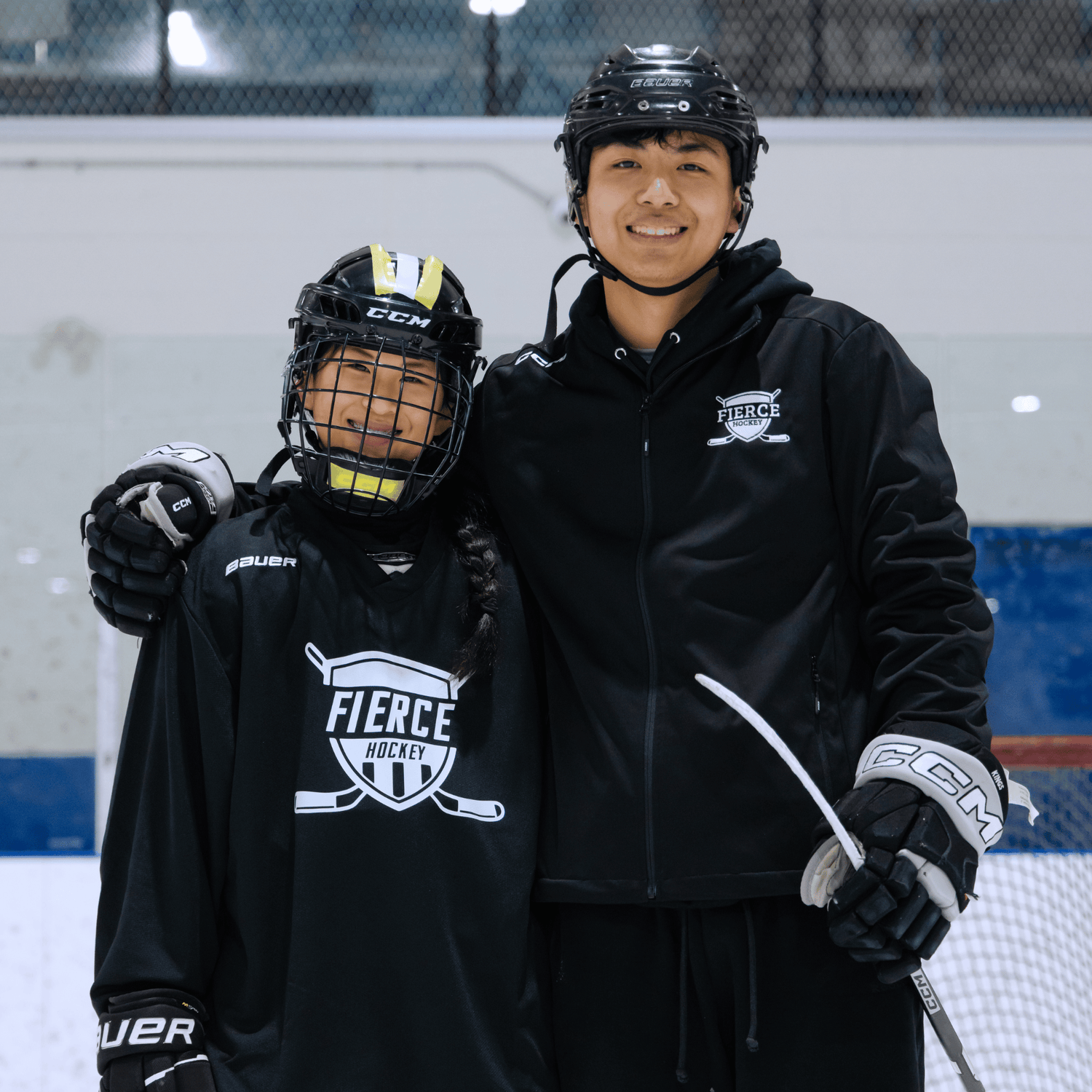 Two individuals in hockey gear posing on an ice rink